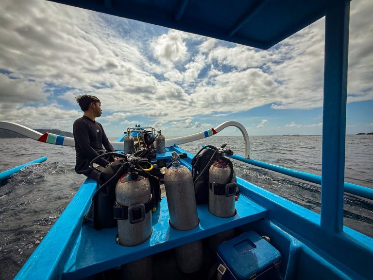 Scenic shot from a dive boat in Candidasa, Bali, with dive guide at the bow and scuba tanks set up for the next dive