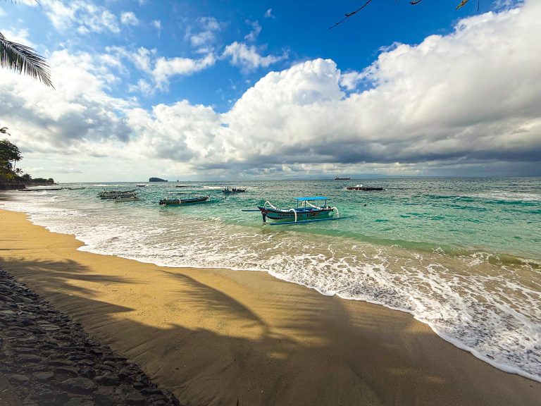 Beach near Sianmay Dive Bali with local boats moored by rope in the sea, Candidasa, Bali